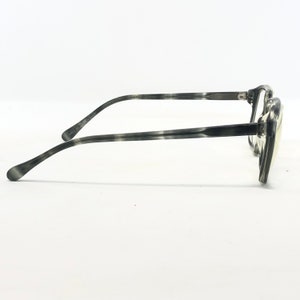 May include: Gray and black patterned eyeglasses with a rectangular frame. The temples and frame have a marbled design. The glasses are set against a white background.