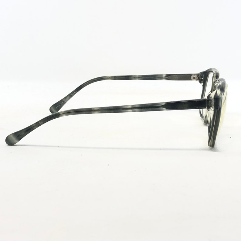 May include: Gray and black patterned eyeglasses with a rectangular frame. The temples and frame have a marbled design. The glasses are set against a white background.