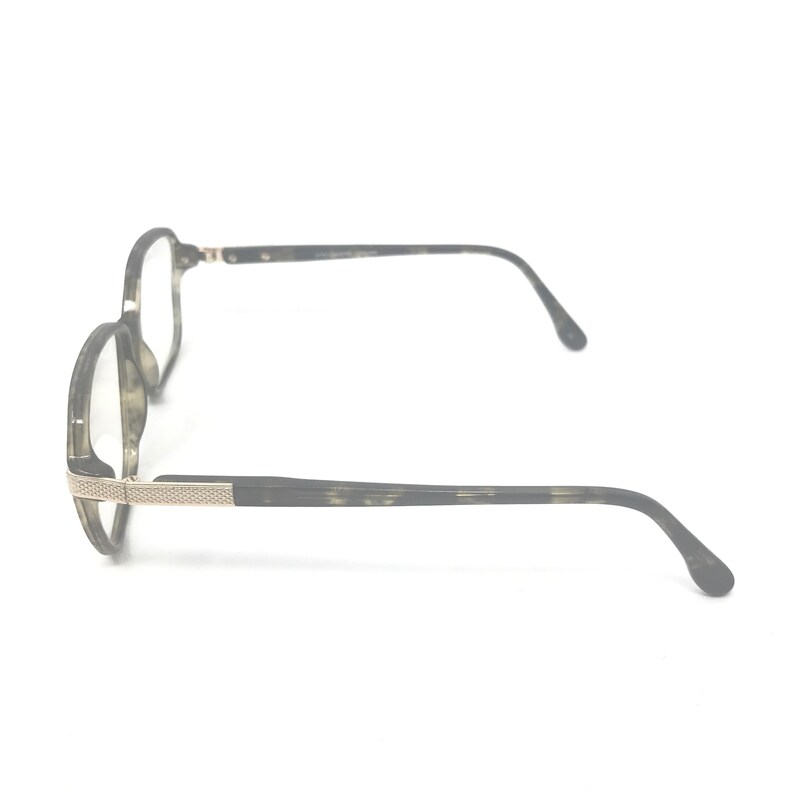 Puede incluir: Un par de gafas con montura redonda y un patr&oacute;n gris oscuro moteado. Las patillas son de color gris oscuro con un detalle plateado cerca de las bisagras. Las lentes son transparentes.