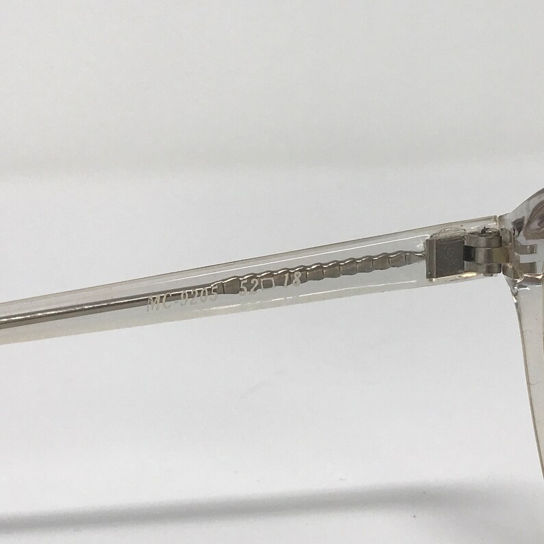 Puede incluir: Primer plano de una montura de gafas transparente. La patilla de las gafas tiene los n&uacute;meros "52 18" impresos. La montura est&aacute; hecha de un material transparente.