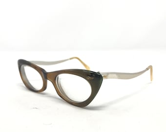 May include: A pair of vintage cat-eye glasses with a brown and white frame. The glasses have clear lenses and a gold accent on the side.