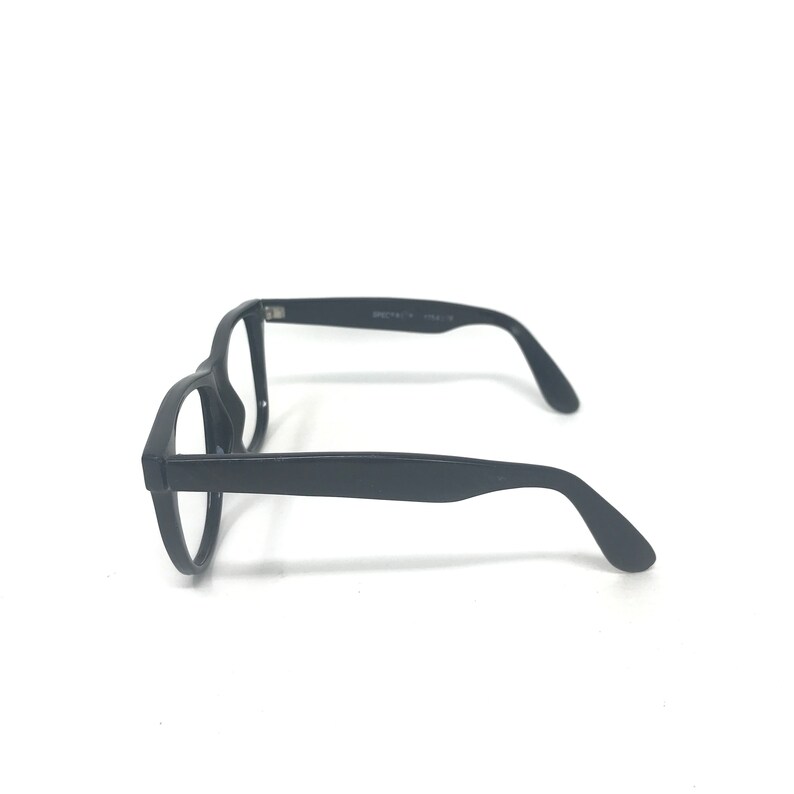 May include: Black eyeglasses with a rectangular frame and curved temples. The glasses are made of a matte black material and are set against a white background. The side of the frame has text printed on it.