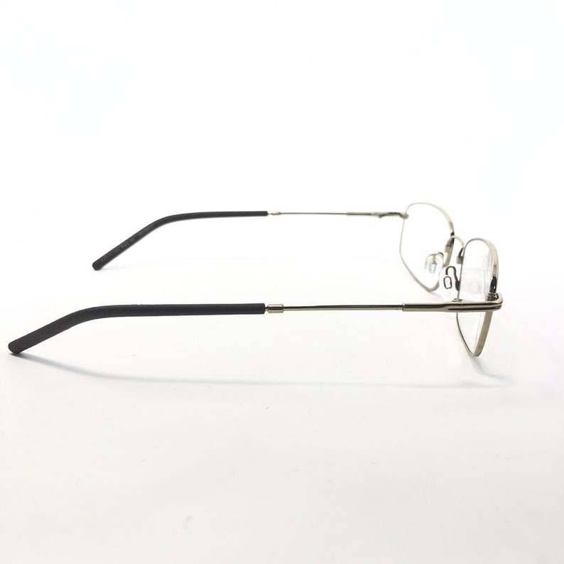 May include: A pair of eyeglasses with a silver metal frame and black temples. The lenses are clear, and the glasses are designed for vision correction. The side view shows the sleek, modern design of the eyewear.