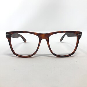 May include: A pair of eyeglasses with a classic tortoiseshell pattern. The frames are a warm brown color with darker speckles, and the lenses are clear. The arms of the glasses are a solid brown color.