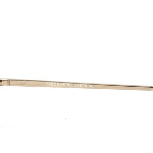 May include: Close-up of a gold-colored eyeglass frame arm. The text "SPECSAVERS 1462056" is printed in black on the arm. The frame appears to be made of metal and has a sleek, modern design.