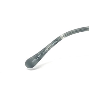 Puede incluir: Primer plano de la patilla de unas gafas. La patilla es de color gris claro con un patr&oacute;n veteado. El texto "54▢18-145 GILES 21054587" est&aacute; impreso en blanco en la patilla.