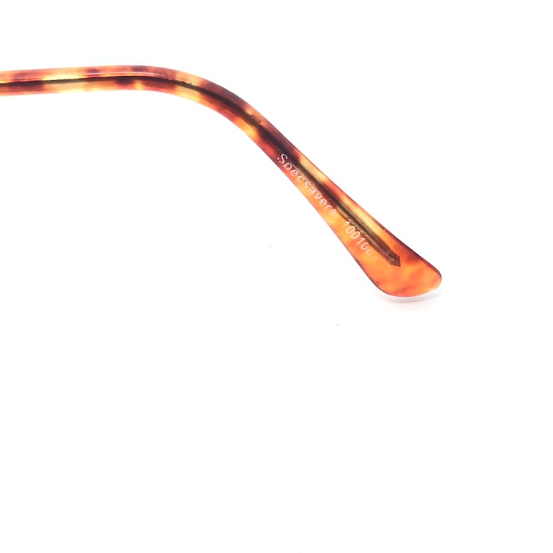 May include: Close-up of the arm of eyeglasses with a tortoiseshell pattern. The arm is brown and tan with the text "Specsavers 100100" printed on the side.