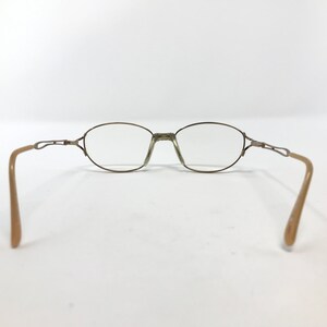 Peut inclure: Une paire de lunettes de vue ovales avec une monture en m&eacute;tal dor&eacute; et des branches en plastique beige.