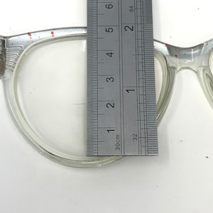 May include: Close-up of a clear plastic frame with a ruler measuring 1 3/8 inches. The frame has a slight orange tint.
