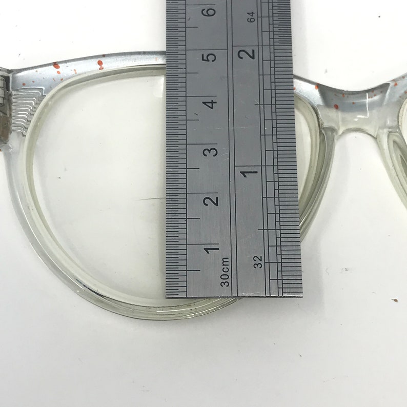 May include: Close-up of a clear plastic frame with a ruler measuring 1 3/8 inches. The frame has a slight orange tint.