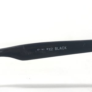 May include: Close-up of the arm of black sunglasses. The text "SUN PX2 BLACK" is printed in white on the black arm. The sunglasses are set against a white background.