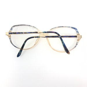 May include: Vintage eyeglasses with clear lenses and a gold-tone metal frame. The frames have a marbled blue and green pattern on the temples and upper rims. The glasses have a classic, oversized shape.
