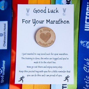 May include: A white card with the text "Good Luck For Your Marathon" and a small wooden token with the text "A little pocket hug".