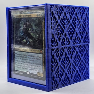 May include: A blue plastic card holder with a decorative pattern. The holder has a clear plastic window to display a Magic: The Gathering card. The card is titled "Ezuri, Claw of Progress" and features an illustration of a green elf warrior with blue energy.