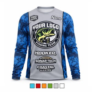 Op de afbeelding: Grijs lange mouwen vissen shirt met blauwe patroon mouwen. Het shirt heeft een grote afbeelding van een vis in een cirkel met de woorden "YOUR LOGO FISHING TEAM". Extra tekst bevat "HOOKED", "SONAR TECH" en "COASTAL MARINE".
