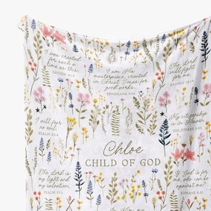 May include: A white floral baby blanket with the name "Chloe" and the words "Child of God" in the center. The blanket is decorated with various floral designs and bible verses.