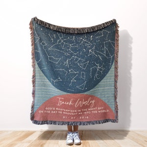 May include: A woven throw blanket with a blue and pink design featuring a constellation map and the text "Isaiah Wesley God's masterpiece in the night sky on the day he brought me into the world. 01-07-2016."