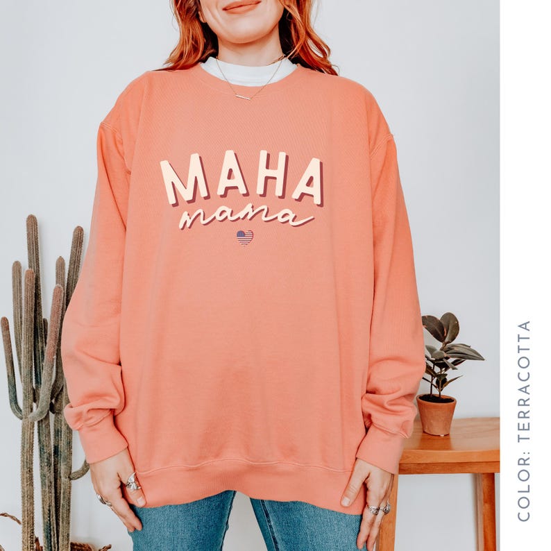 May include: Terracotta colored sweatshirt with the text "MAHA mama" in a retro font with a small American flag heart.