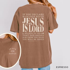 以下が含まれることがあります： 白のセラミックマグカップ、黒いハンドル、手書き風の「But First, Coffee」の文字。マグカップは白い表面に置かれています。マグカップの高さは10cmです。