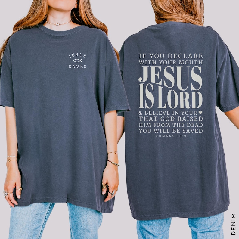 以下が含まれることがあります： 前面に「JESUS SAVES」の文字と魚のシンボルが入ったデニムブルーのTシャツ。Tシャツの背面には「IF YOU DECLARE WITH YOUR MOUTH JESUS IS LORD & BELIEVE IN YOUR THAT GOD RAISED HIM FROM THE DEAD YOU WILL BE SAVED ROMANS 10 9」の文字が入っています。