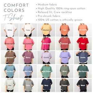 以下が含まれることがあります： 白、アイボリー、マスタード、赤など、さまざまな色のComfort Colors Tシャツの品揃え。各シャツの下に色の名前が表示されています。画像には「Comfort Colors T-Shirt」というテキストも含まれています。