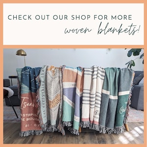 Puede incluir: Una exhibici&oacute;n de mantas tejidas en varios colores y dise&ntilde;os, algunas con texto. Las mantas est&aacute;n colgadas sobre una estructura de madera. El texto en la imagen dice: "CHECK OUT OUR SHOP FOR MORE woven blankets!"