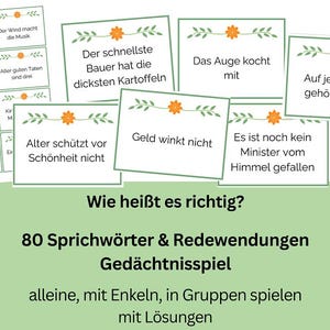 Könnte beinhalten: Ein Set mit 80 deutschen Sprichwörtern und Redensarten für ein Gedächtnisspiel. Die Karten sind grün mit orangenen Blumen und der Text ist schwarz. Das Spiel heißt "Wie heißt es richtig?"