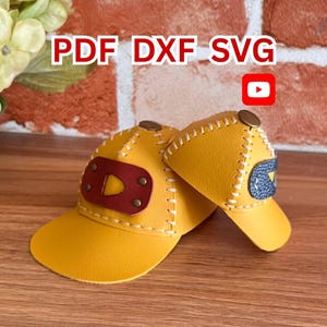 May include: Two yellow baseball caps with stitched detailing and brown accents. One cap has a red and brown patch, the other has a blue and white patch. The text "PDF DXF SVG" is visible.