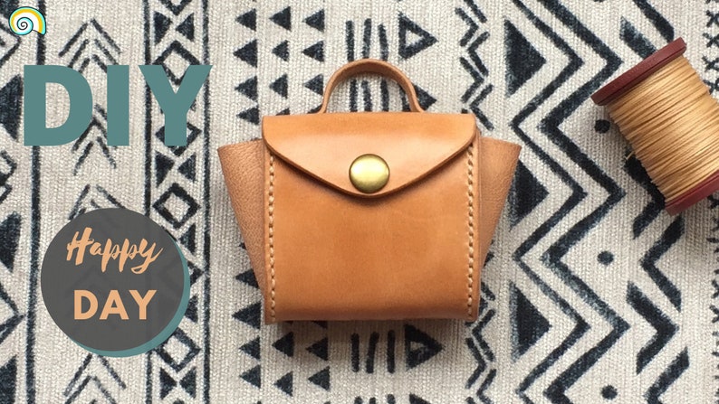 A small brown leather storage bag with a gold button and a reel of beige thread.