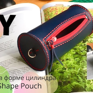 May include: DIY Cylinder Shape Pouch, a blue leather pouch with a red zipper and red stitching. The pouch is lying on a book with the text "DIY" and "Cylinder Shape Pouch" visible.