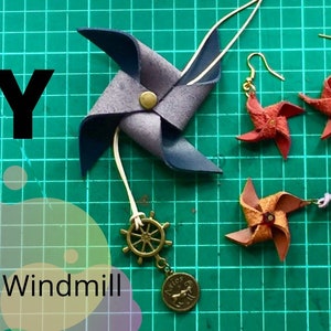 May include: DIY leather windmill necklace and earrings. The necklace features a brown leather windmill with a gold metal wheel charm. The earrings are red leather windmills with gold hooks.