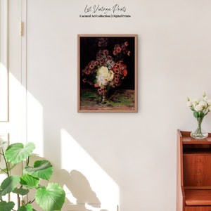 May include: A framed vintage painting of a still life featuring a bouquet of flowers in a glass vase. The flowers are a mix of white, pink, and red, and the vase is sitting on a table with a green tablecloth. The painting is set against a dark background.