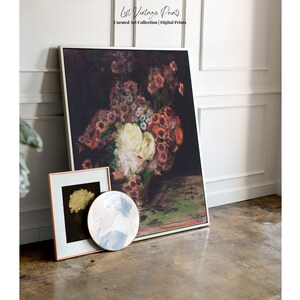 May include: A framed print of a still life painting featuring a bouquet of red, white, and pink flowers in a vase. The flowers are arranged in a vase on a dark green table. The painting is framed in a white frame.