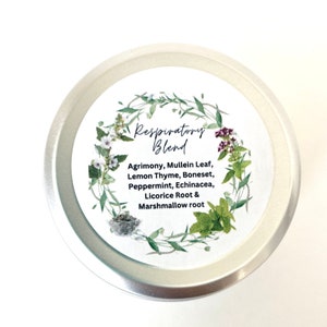 Puede incluir: Una lata de plata con una etiqueta blanca que dice "Respiratory Blend" y enumera los ingredientes: Agrimonia, hoja de gordolobo, tomillo limón, hierba de hueso, menta piperita, equinácea, raíz de regaliz y raíz de malvavisco. La etiqueta está rodeada por una corona de hojas verdes y flores.