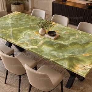 Könnte beinhalten: Ein rechteckiger Esstisch mit einer polierten Tischplatte aus grünem Onyx mit natürlichen weißen und goldenen Maserungen, getragen von einem schwarzen Metallgestell. Der Tisch ist von sechs beigen Polsterstühlen mit dunklen Beinen umgeben.