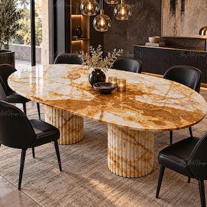 Peut inclure: Une table à manger ovale dotée d'un plateau en marbre poli aux tons ambrés et blancs avec des veines marquées. La table repose sur deux pieds cylindriques cannelés en marbre assorti, entourée de six chaises rembourrées noires.