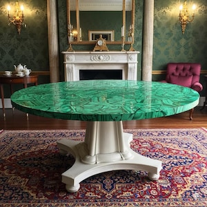 Può includere: Un grande tavolo rotondo con un piano in malachite verde vibrante. Il tavolo ha una base a piedistallo bianca con quattro piedi. Il tavolo è posto su un tappeto fantasia in una stanza con decorazioni ornate.