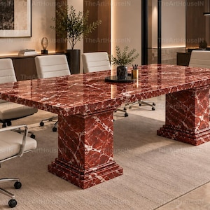 Peut inclure: Une grande table de conférence rectangulaire dotée d'une surface en marbre rouge poli avec des veines blanches, soutenue par deux bases piédestales en marbre assorties. La table est entourée de plusieurs chaises de bureau blanches.