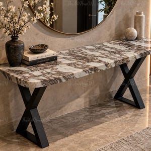 Pode incluir: Uma mesa consola com um tampo retangular de padrão de mármore branco e castanho e duas pernas de metal preto em forma de X. A superfície da mesa contém um vaso escuro com flores brancas, uma pequena taça, dois livros, uma esfera e um vaso alto.