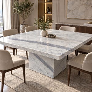Puede incluir: Una mesa de comedor cuadrada con un tablero de mármol blanco con vetas grises y una base de pedestal a juego. La mesa está rodeada por cuatro sillas tapizadas con tela beige claro y patas de madera oscura sobre una alfombra texturizada.