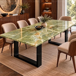 Puede incluir: Una mesa de comedor rectangular con un tablero de piedra de ónix verde pulido con vetas naturales blancas y doradas, sostenida por una base de metal negro en forma de U, rodeada de seis sillas tapizadas con estructura de madera.