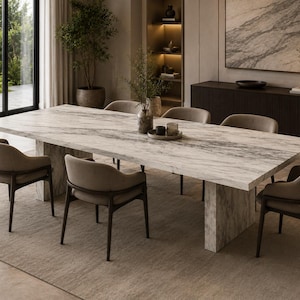 Peut inclure: Une table à manger rectangulaire avec un plateau en marbre blanc et gris et des pieds en dalle assortis, entourée de six fauteuils dotés de cadres en bois foncé et de sièges rembourrés beige clair, disposés sur un grand tapis neutre.