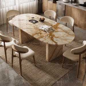 Pode incluir: Uma mesa de jantar oval com tampo de mármore polido em tons creme e dourado sobre uma base de pedestal espessa, rodeada por seis cadeiras com estruturas de madeira curvas e assentos estofados em bege claro sobre um tapete tecido.