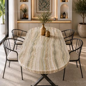 Puede incluir: Una mesa de comedor ovalada con un tablero de mármol pulido en tonos verde claro y beige con vetas naturales, apoyada sobre una base de metal negro en forma de X. Cuatro sillas negras de respaldo de varillas con asientos beige.