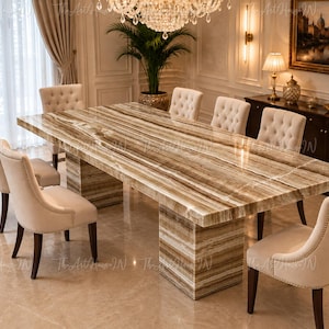 Puede incluir: Una mesa de comedor rectangular con tablero y base de piedra pulida en tonos marrón y crema, rodeada por ocho sillas tapizadas en color beige con capitoné y patas de madera oscura en un comedor formal.