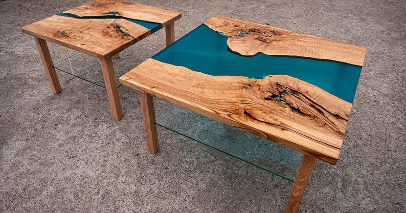 May include: Two wooden side tables with a live edge design and teal epoxy resin inlays. The tables have natural wood grain and are supported by four wooden legs. The tables are approximately 24 inches long and 18 inches wide.