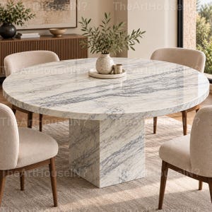 May include: A round dining table with a white and grey marble top and a matching cylindrical marble pedestal base. Four upholstered chairs with light beige fabric and wooden legs are positioned around the table. A ceramic vase with greenery sits on a tray.