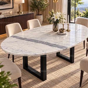 Puede incluir: Una mesa de comedor ovalada con una superficie de mármol blanco con vetas grises y una franja central gris oscuro. La mesa se apoya en dos patas de metal negro en forma de U y está rodeada por seis sillas tapizadas en beige con patas de madera oscura.