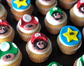 Könnte beinhalten: Eine Sammlung von dekorierten Cupcakes mit verschiedenen Mario-Charakteren und Symbolen. Die Cupcakes sind mit grünem, rotem, gelbem und blauem Frosting und Fondant verziert.