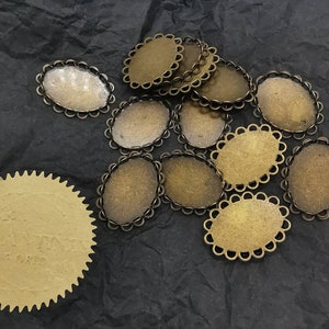 May include: A group of 14 oval-shaped metal frames with a decorative scalloped edge. The frames are brass in colour and have a shiny finish.